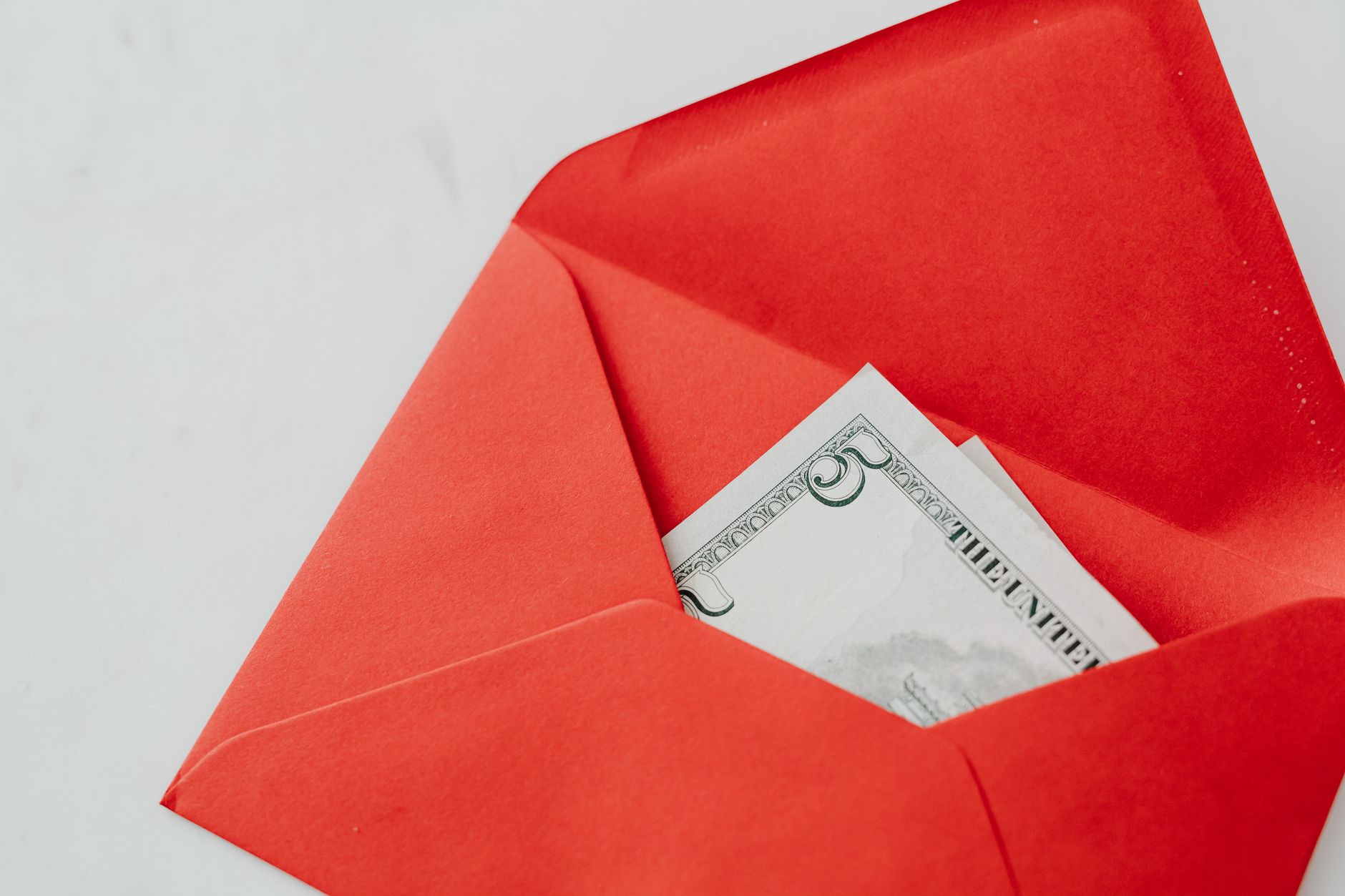 Red cash envelope with a US dollar bill inside on a white background